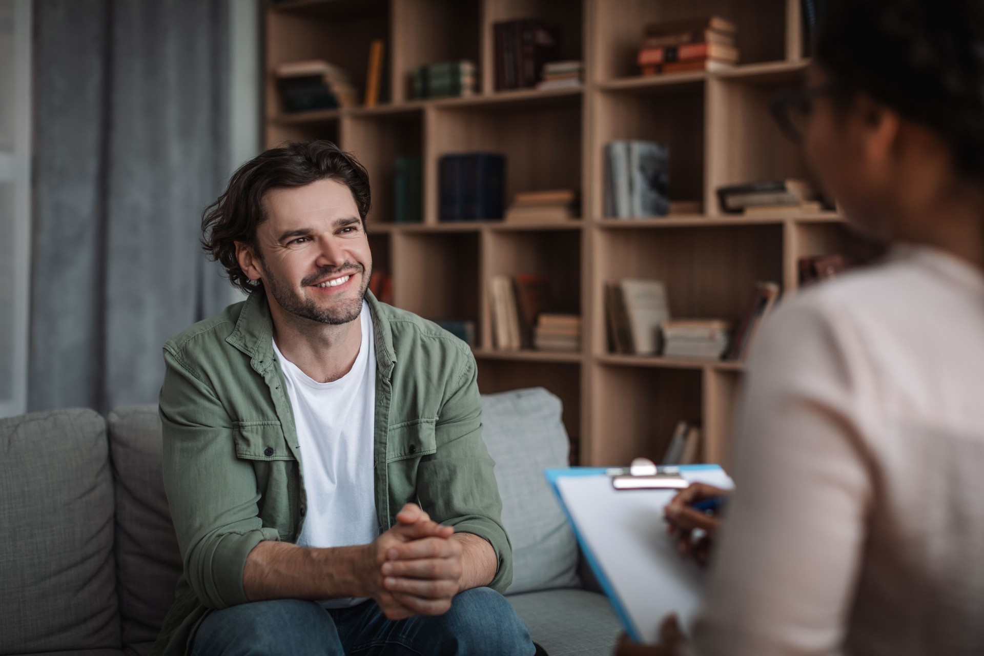 Millennial black woman psychologist consults smiling european guy in modern clinic interior