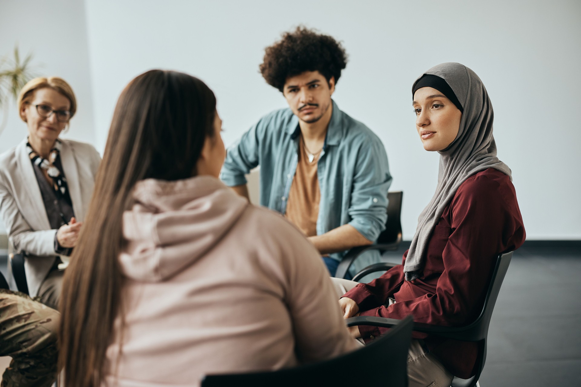 Multi-ethnic people having counseling during group therapy meeting at community center.